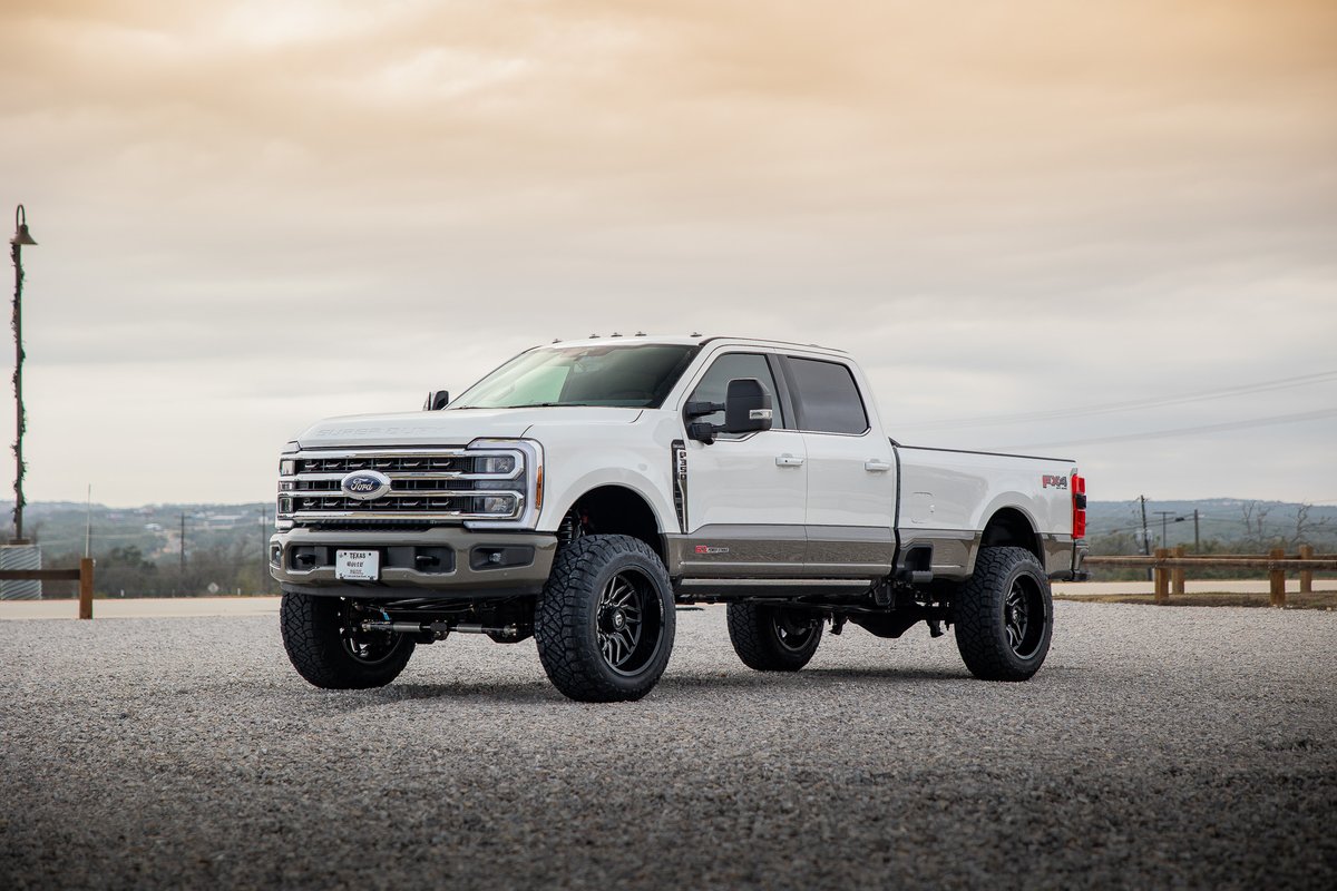 White Ford F-350 Super Duty King Ranch lifted with custom black rims, and two-tone trim.