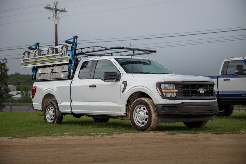 White 2026 Ford F-150 work truck with ladder rack and bed storage.