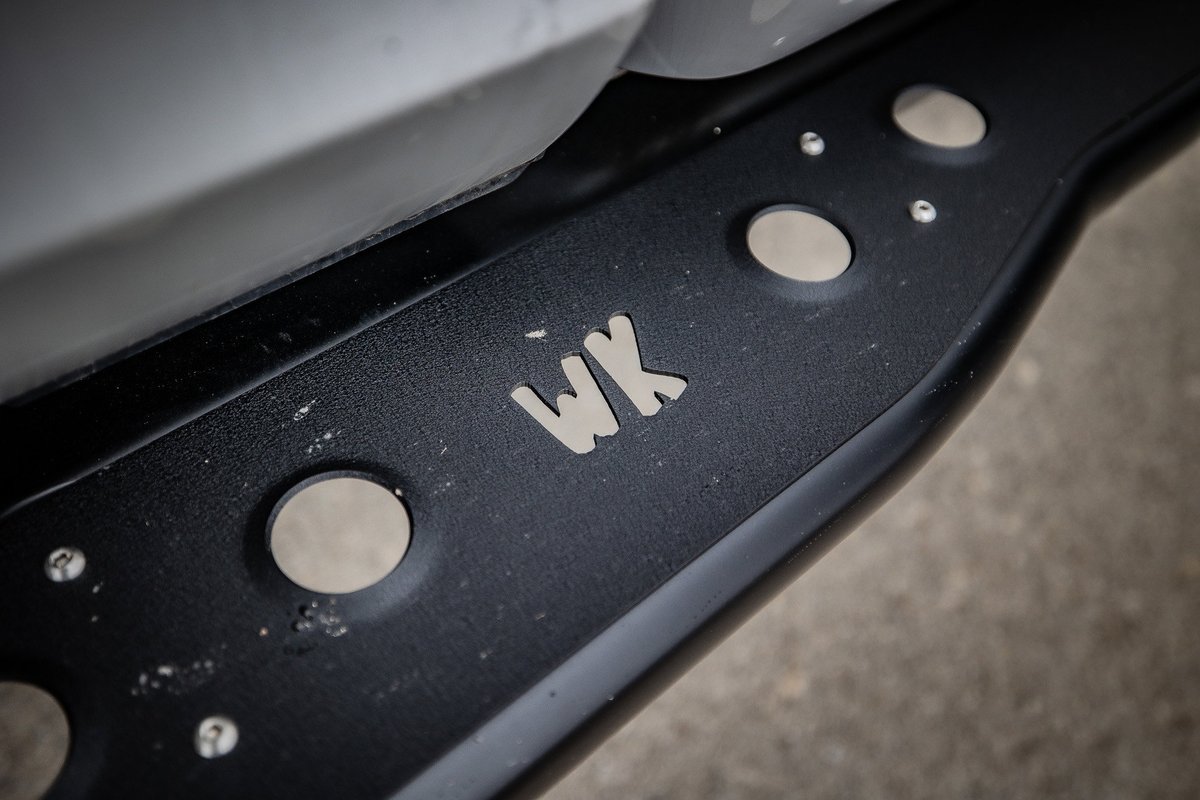 Close-up of a black WK step with circular cutouts on a silver vehicle.