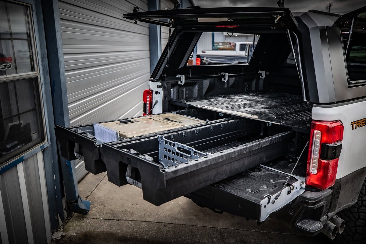 White Toyota Tacoma TRD Pro truck bed with sliding storage drawers and black truck cap.